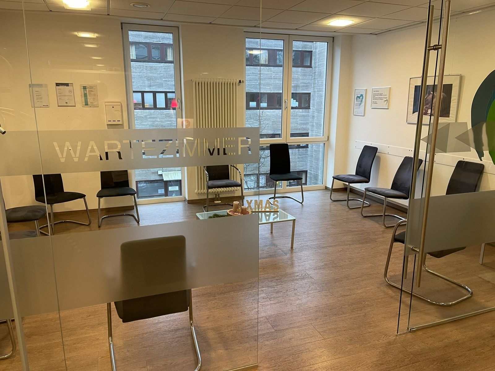 Wartezimmer: Ein heller Raum mit großen Fenstern, in dem Sie bis zu Ihrem Termin Platz nehmen.